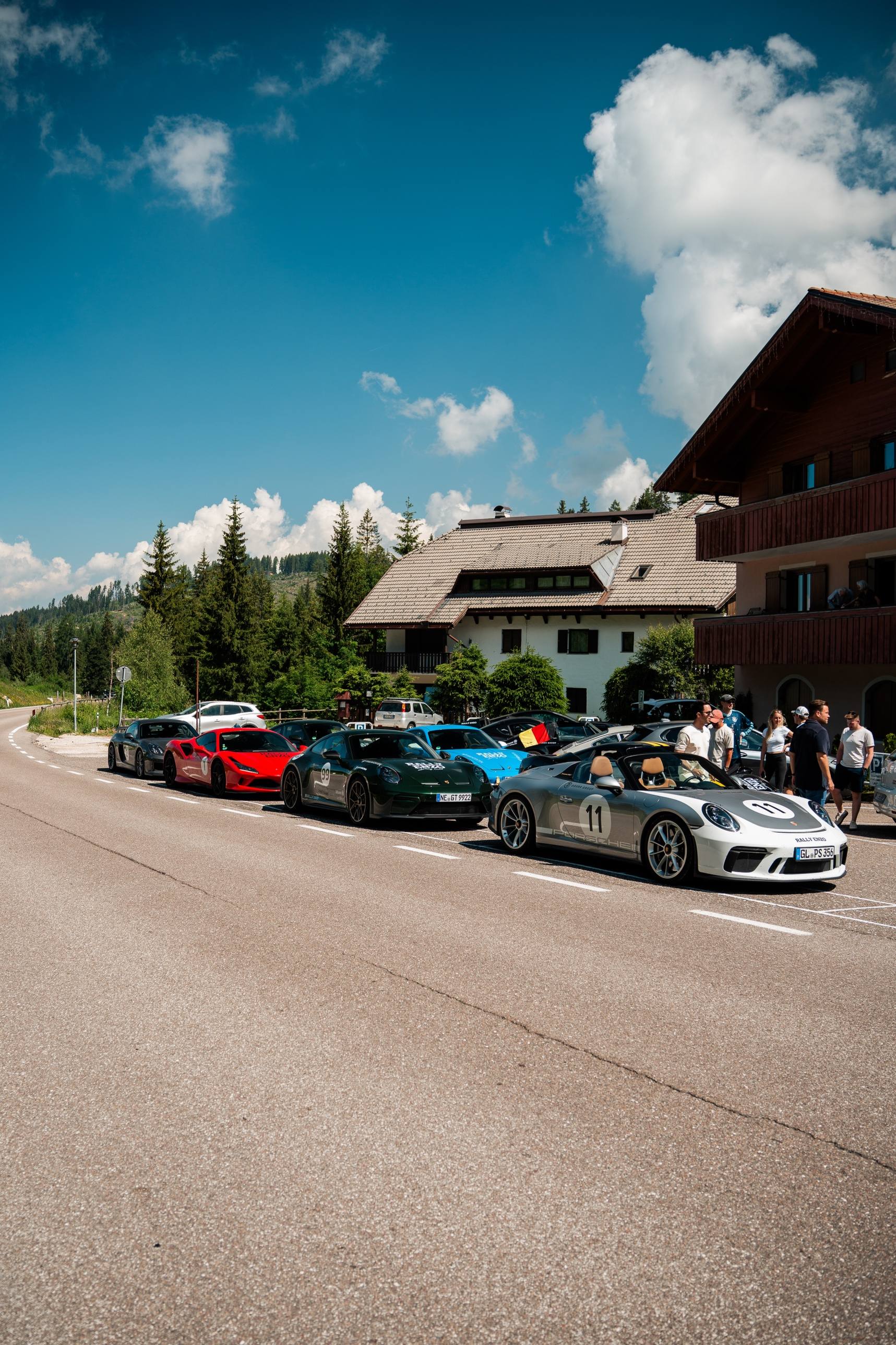 Sportwagen in einer Reihe vor einem Alpenhotel, Porsche Speedster mit Startnummer 11 vorn