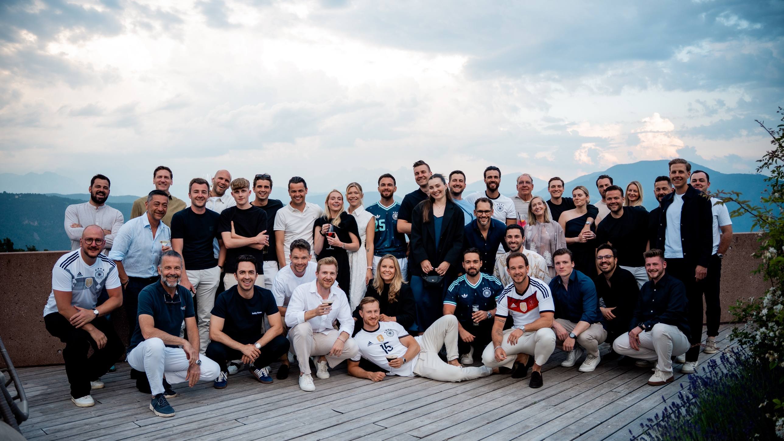 Gruppenfoto aller Teilnehmer auf einer Hotelterrasse vor Bergen