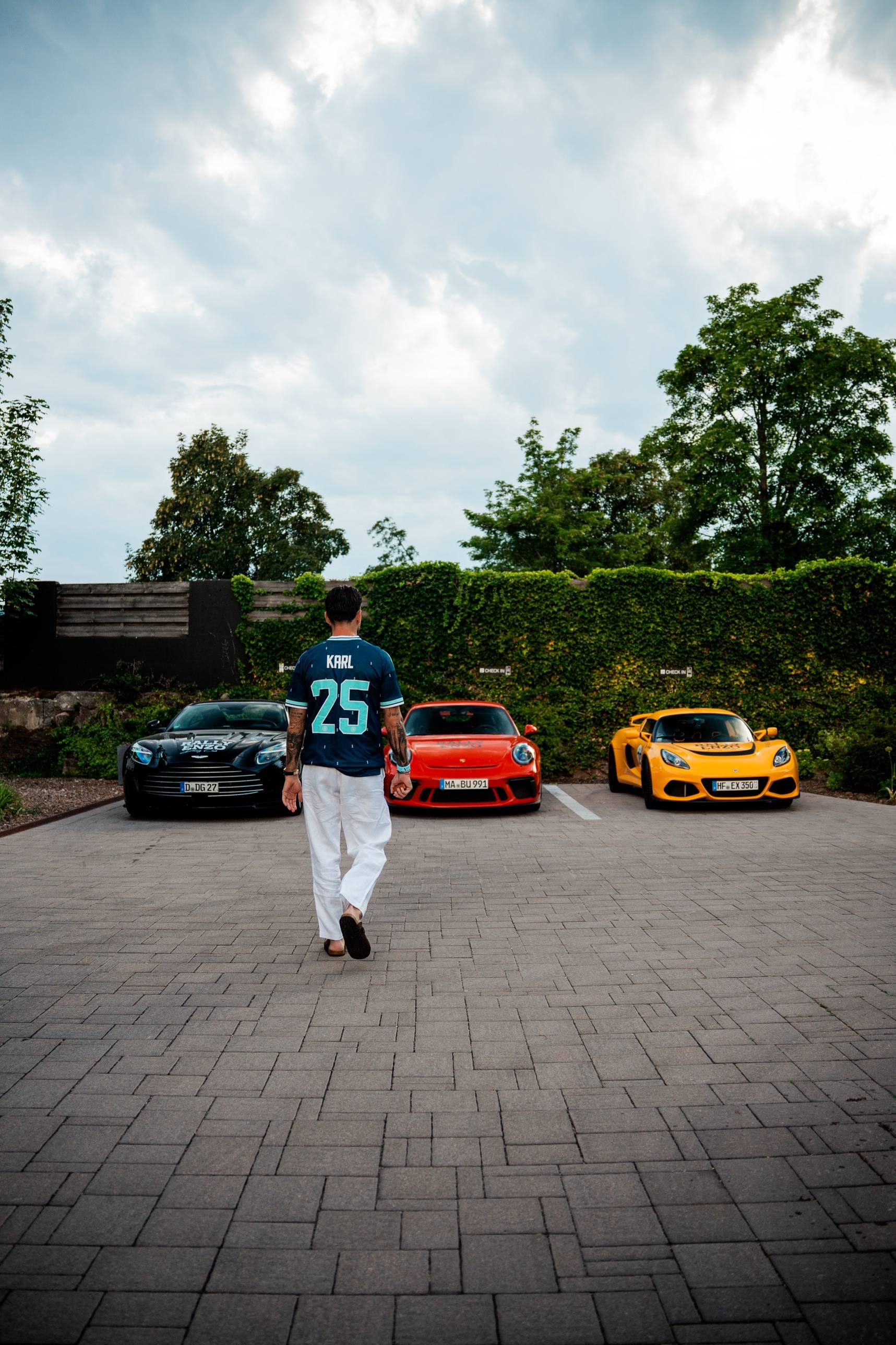 Teilnehmer im Trikot mit der Nummer 25 geht auf Aston Martin, Porsche und Lotus zu