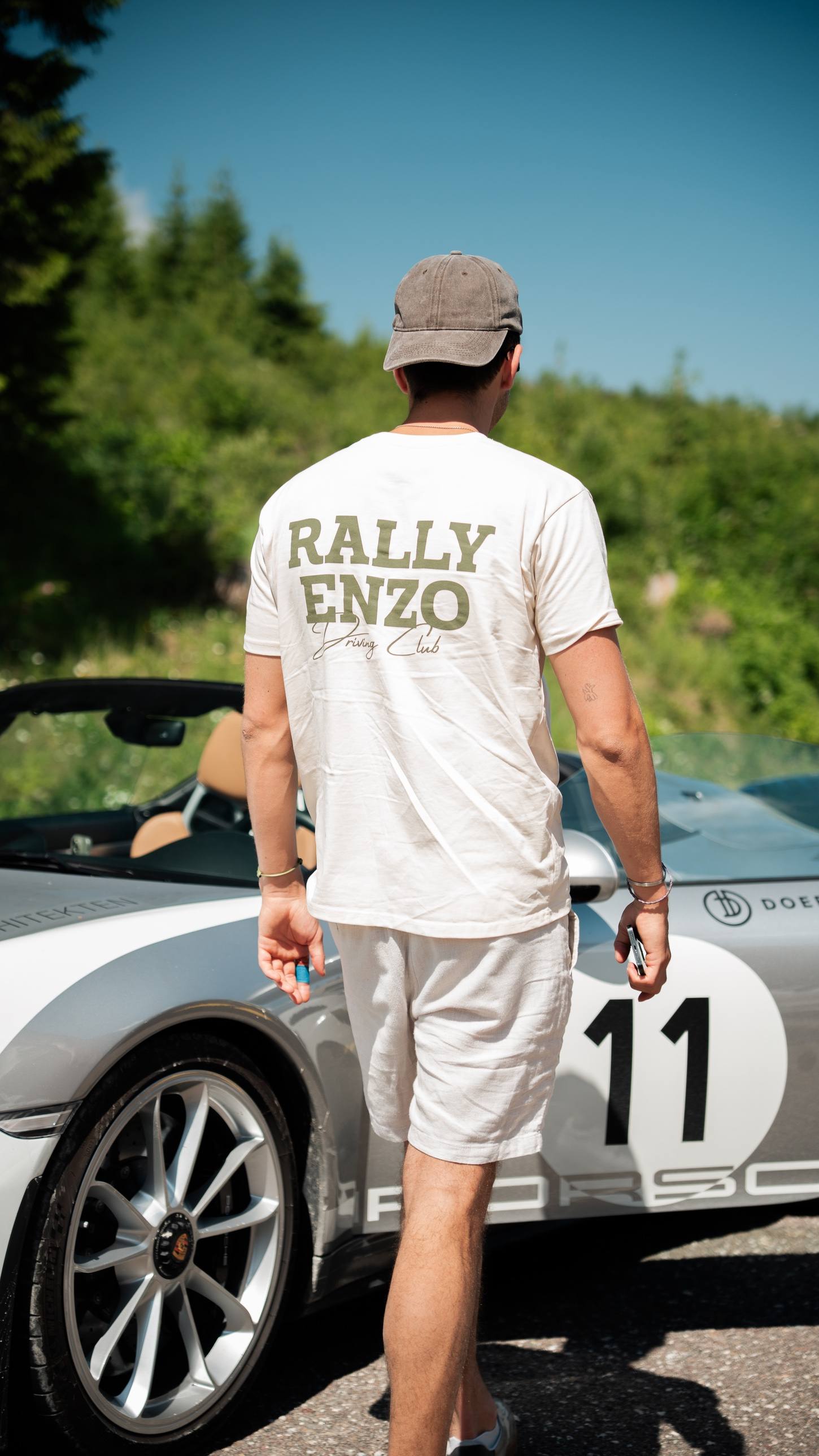 Teilnehmer im RALLY-ENZO-Driving-Club-Shirt vor dem Porsche mit Startnummer 11